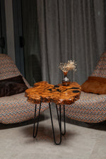 AI-styled view of Zitun Atelier table 049, an olive wood resin small coffee table with black resin spots, in a lounge setting with a vase on the tabletop.