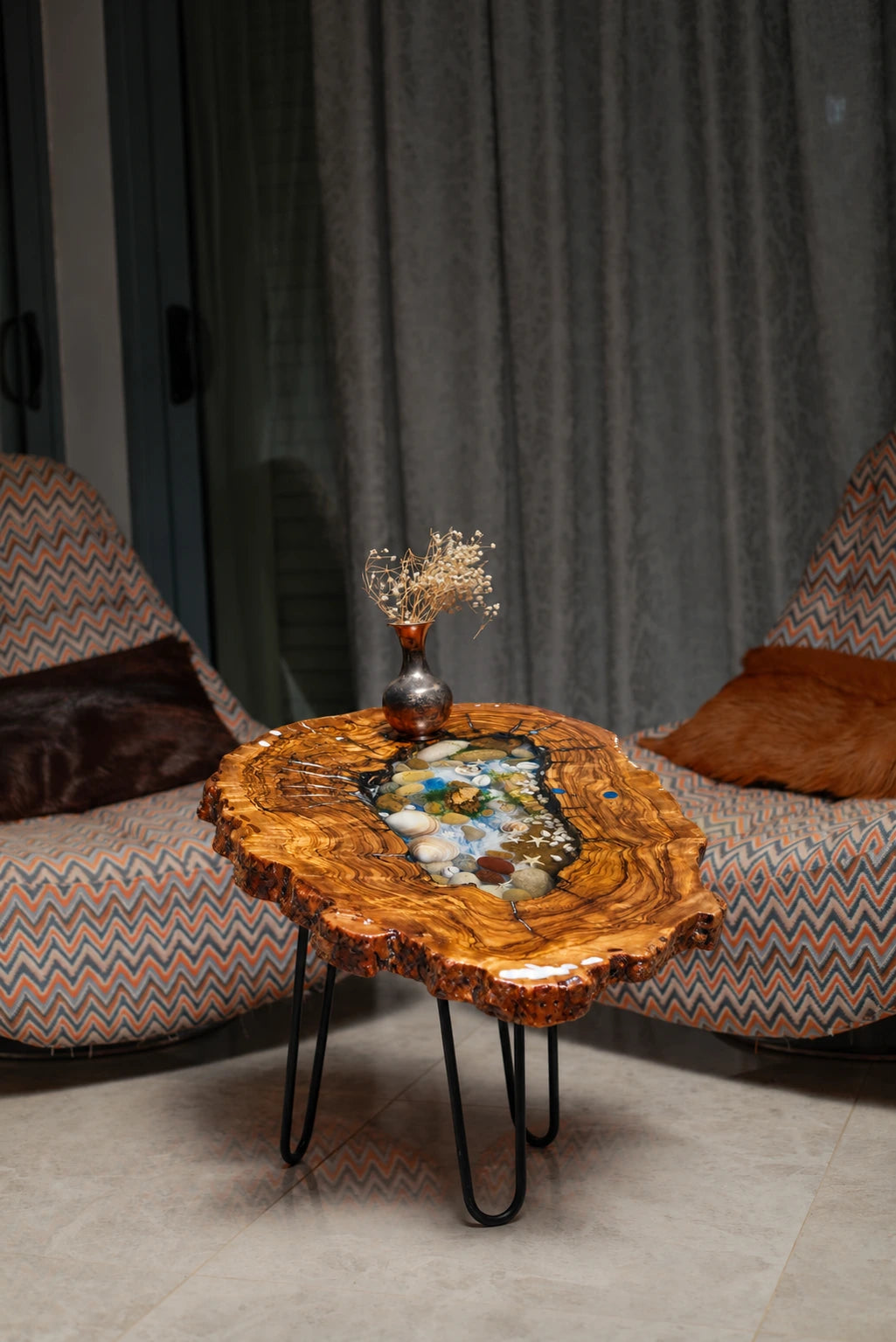 AI-styled view of Zitun Atelier table 052, an olive wood resin side table with sea shell pebble resin, in a lounge setting with a vase on the tabletop.