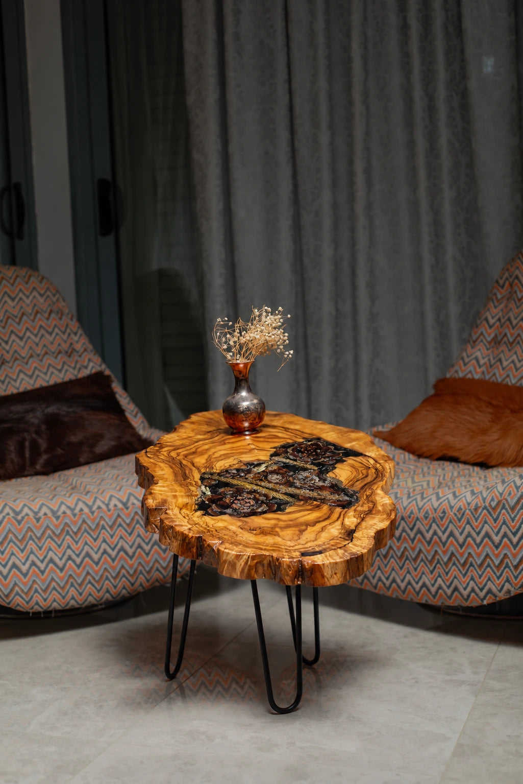 AI-styled view of Zitun Atelier table 053, an olive wood resin side table with pine cone black resin, in a lounge setting with a vase on the tabletop.