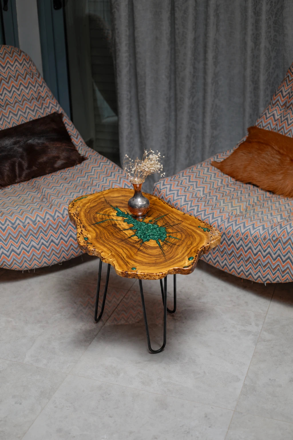 AI-styled view of Zitun Atelier table 054, an olive wood resin side table with green malachite starburst resin, viewed from above between two upholstered armchairs.