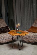 AI-styled view of Zitun Atelier table 054, an olive wood resin side table with green malachite starburst resin, in a lounge setting with a vase on the tabletop.