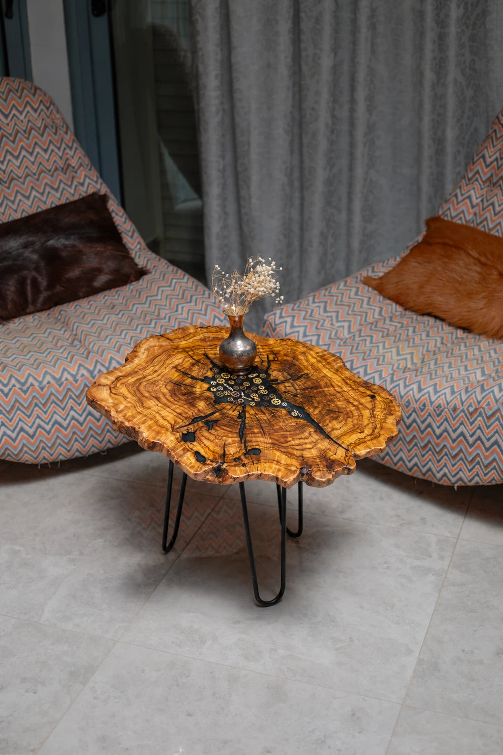 AI-styled view of Zitun Atelier table 055, an olive wood resin small coffee table with black resin clock gears, viewed from above between two upholstered armchairs.
