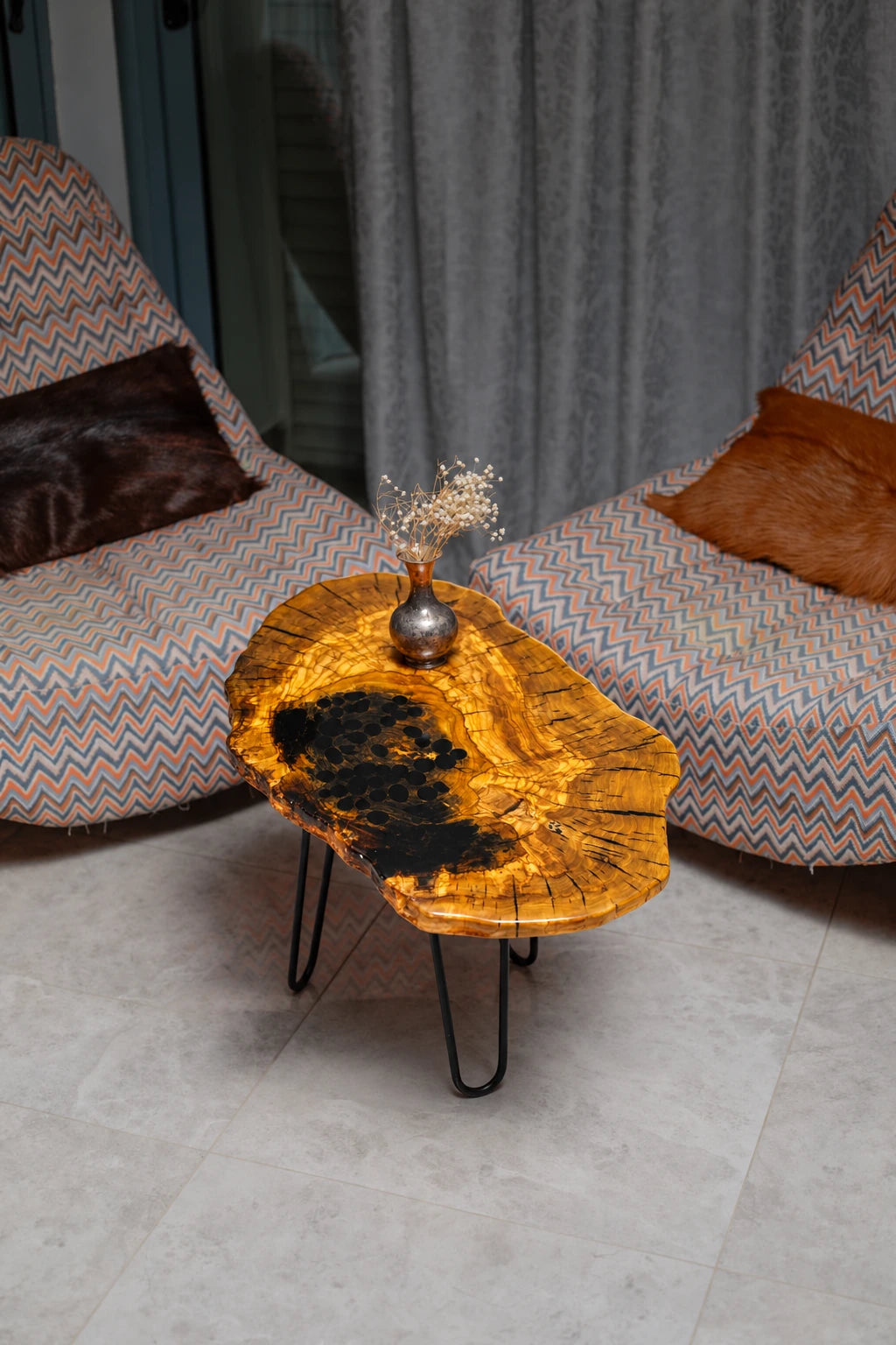 AI-styled view of Zitun Atelier table 056, an olive wood resin side table with black resin, viewed from above between two upholstered armchairs.