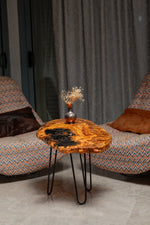 AI-styled view of Zitun Atelier table 056, an olive wood resin side table with black resin, in a lounge setting with a vase on the tabletop.