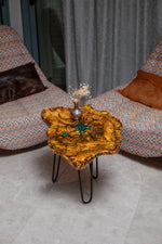 AI-styled view of Zitun Atelier table 057, an olive wood resin side table with emerald green star resin, viewed from above between two upholstered armchairs.