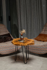 AI-styled view of Zitun Atelier table 059, an olive wood resin side table with white resin center, in a lounge setting with a vase on the tabletop.