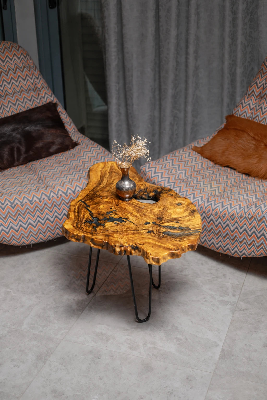 AI-styled view of Zitun Atelier table 060, an olive wood resin side table with dark blue resin veins, viewed from above between two upholstered armchairs.
