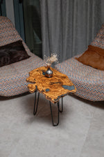 AI-styled view of Zitun Atelier table 062, an olive wood resin side table with blue resin pools, viewed from above between two upholstered armchairs.