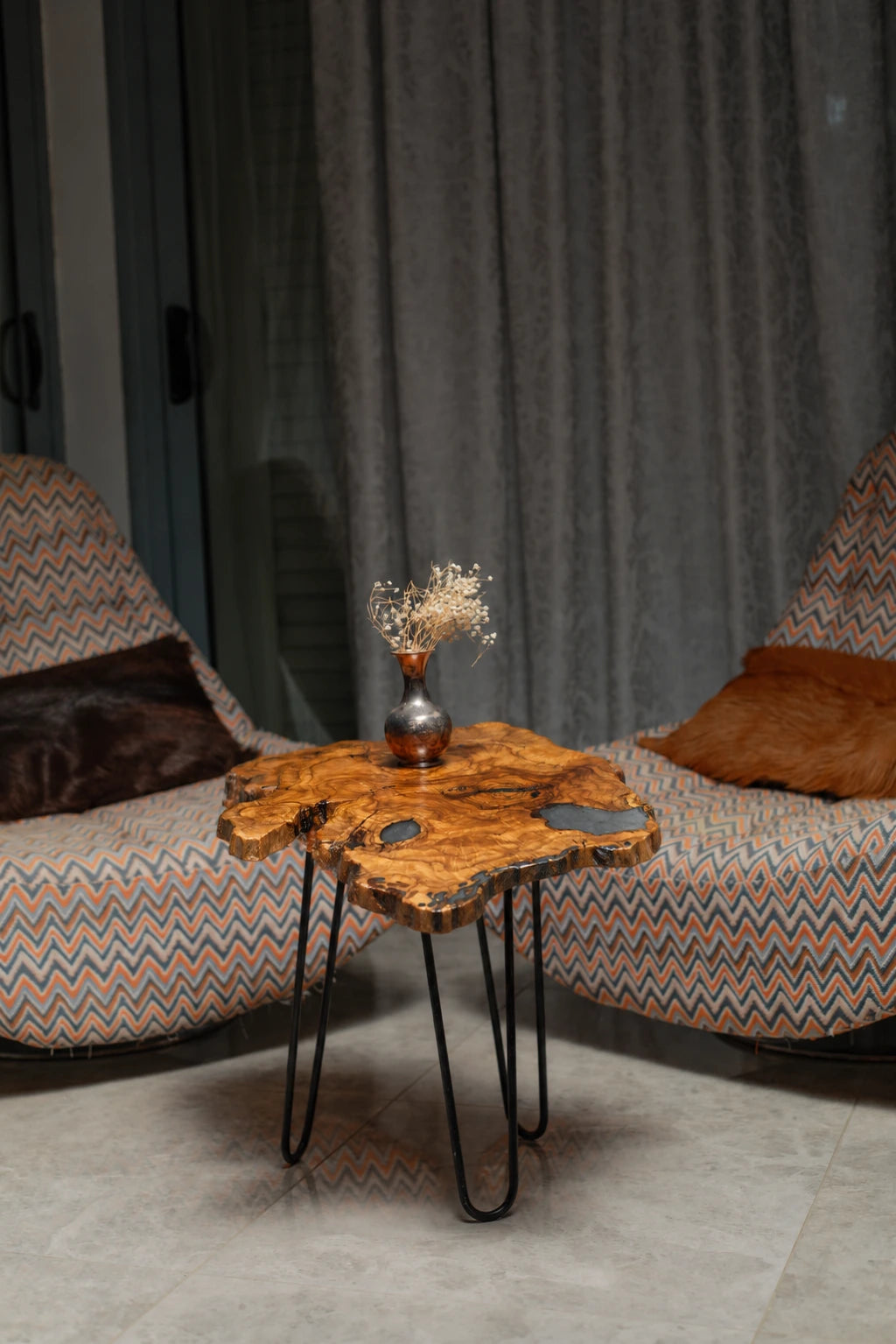 AI-styled view of Zitun Atelier table 062, an olive wood resin side table with blue resin pools, in a lounge setting with a vase on the tabletop.