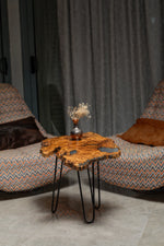 AI-styled view of Zitun Atelier table 062, an olive wood resin side table with blue resin pools, in a lounge setting with a vase on the tabletop.