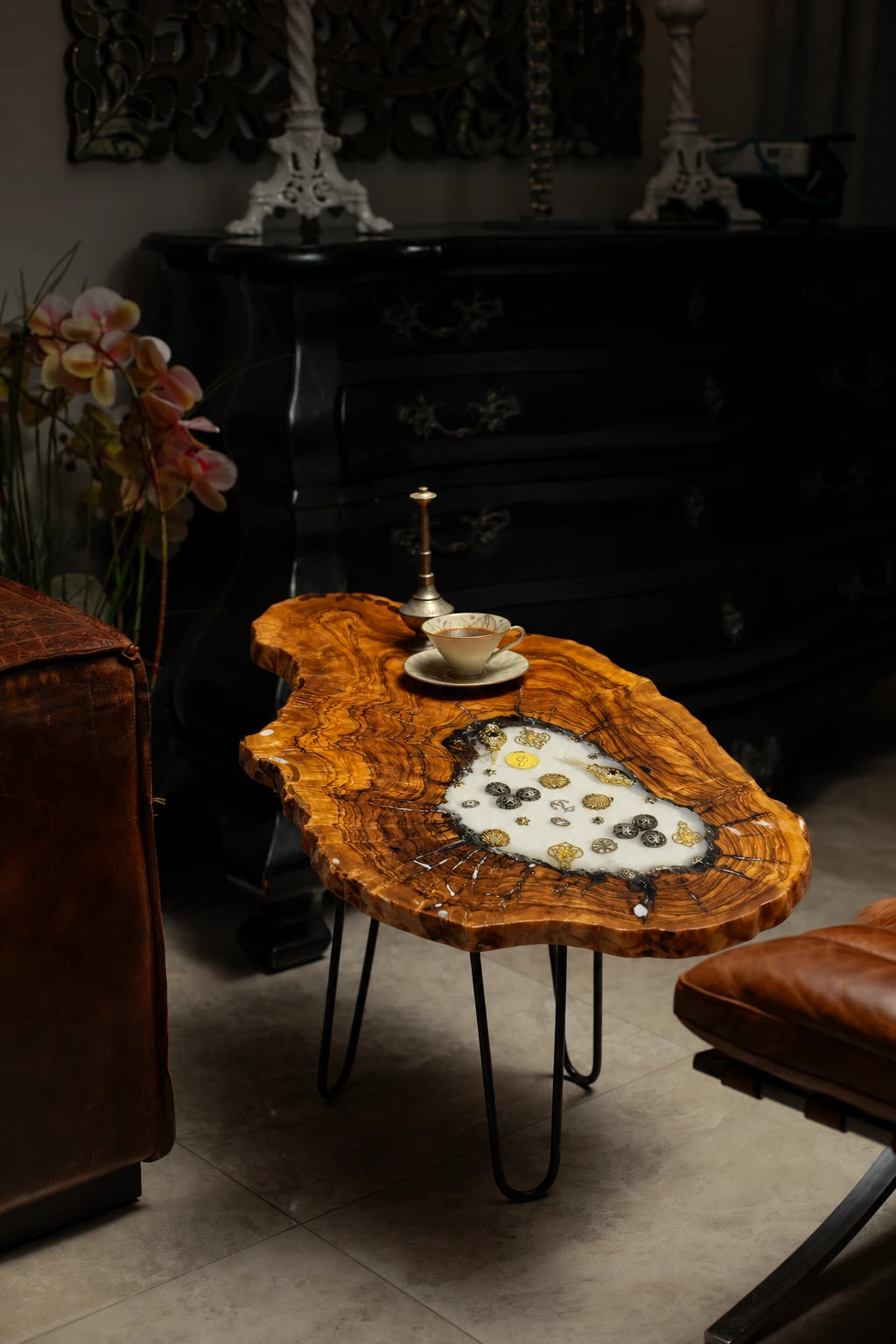 AI-styled view of Zitun Atelier table 063, an olive wood resin side table with white resin vintage coins, in a dark interior beside leather seating.