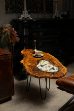 AI-styled view of Zitun Atelier table 063, an olive wood resin side table with white resin vintage coins, in a dark interior beside leather seating.