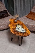 AI-styled view of Zitun Atelier table 063, an olive wood resin side table with white resin vintage coins, viewed from above between two upholstered armchairs.