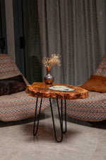 AI-styled view of Zitun Atelier table 063, an olive wood resin side table with white resin vintage coins, in a lounge setting with a vase on the tabletop.