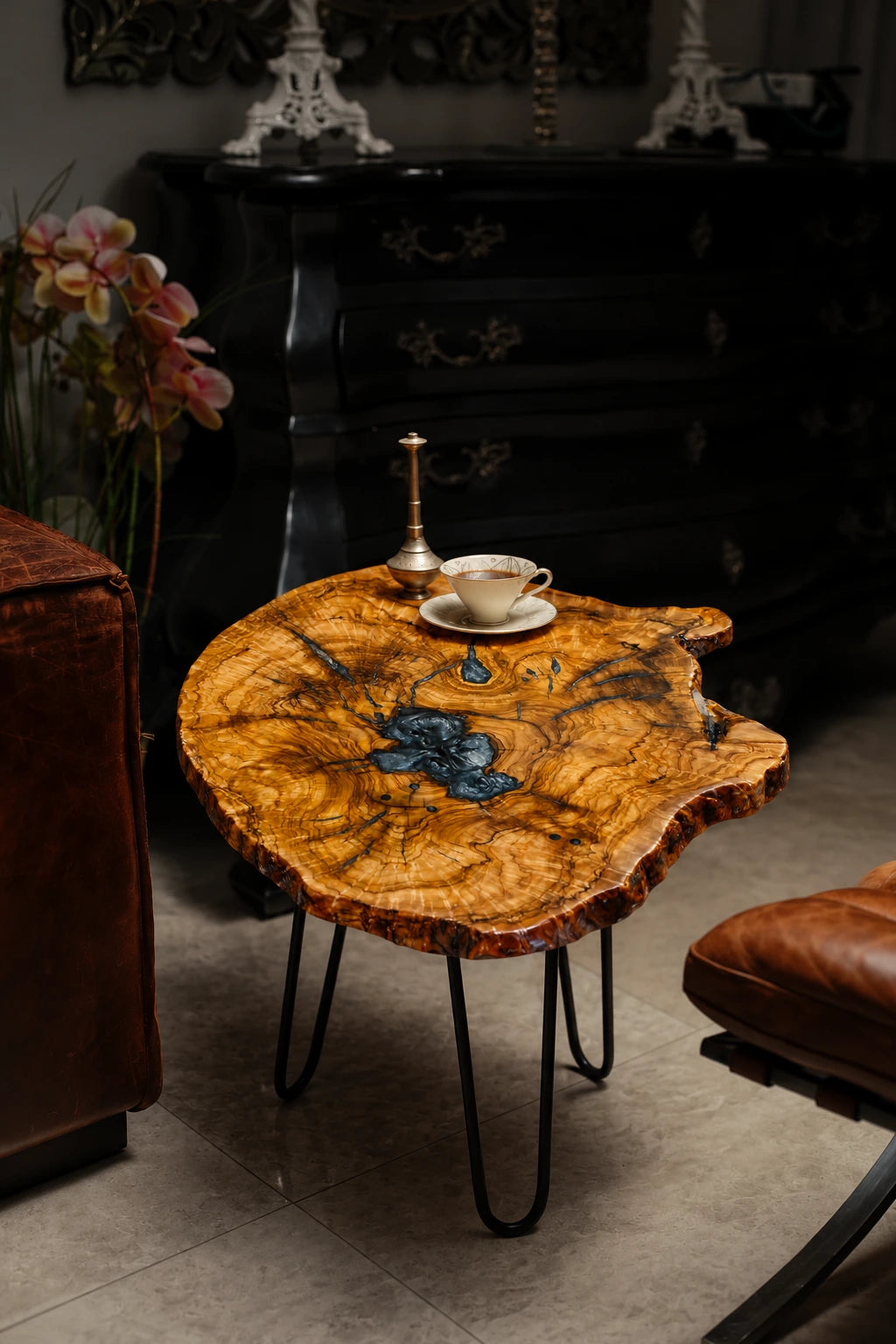 AI-styled view of Zitun Atelier table 064, an olive wood resin side table with metallic blue resin, in a dark interior beside leather seating.