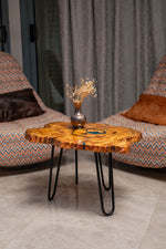AI-styled view of Zitun Atelier table 065, an olive wood resin side table with blue resin ring, in a lounge setting with a vase on the tabletop.