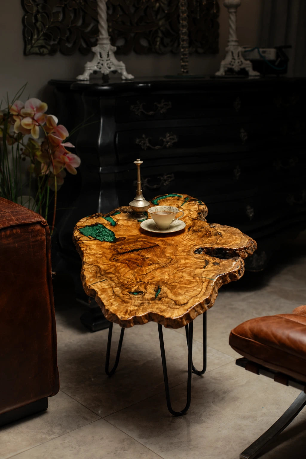 AI-styled view of Zitun Atelier table 068, an olive wood resin small coffee table with emerald green resin edge, in a dark interior beside leather seating.