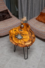 AI-styled view of Zitun Atelier table 069, an olive wood resin side table with white resin center, viewed from above between two upholstered armchairs.