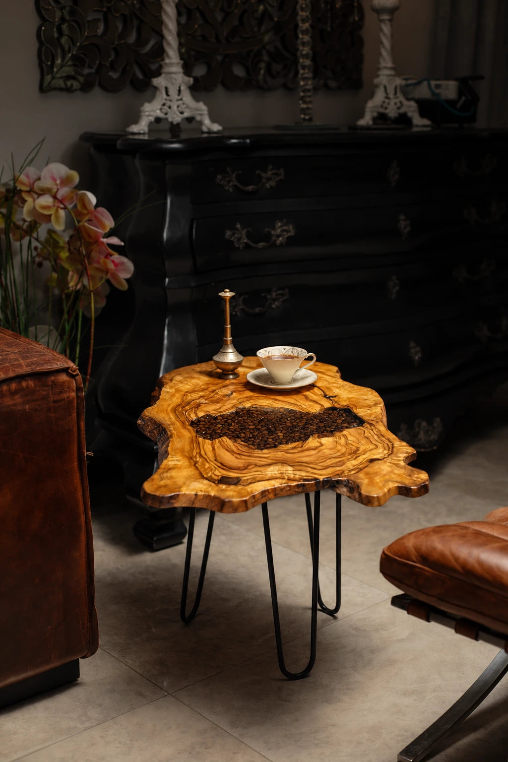 AI-styled view of Zitun Atelier table 070, an olive wood resin side table with coffee bean resin, in a dark interior beside leather seating.
