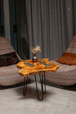 AI-styled view of Zitun Atelier table 073, an olive wood resin small coffee table with blue grey resin, in a lounge setting with a vase on the tabletop.