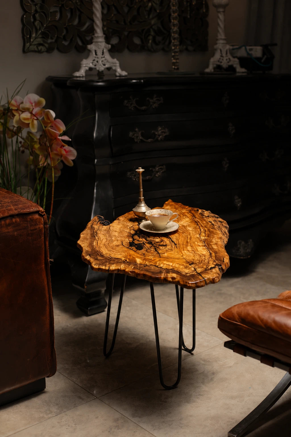 AI-styled view of Zitun Atelier table 074, an olive wood resin side table with black resin veins, in a dark interior beside leather seating.
