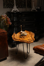 AI-styled view of Zitun Atelier table 074, an olive wood resin side table with black resin veins, in a dark interior beside leather seating.
