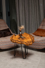 AI-styled view of Zitun Atelier table 074, an olive wood resin side table with black resin veins, in a lounge setting with a vase on the tabletop.
