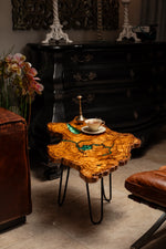 AI-styled view of Zitun Atelier table 075, an olive wood resin small coffee table with turquoise resin veins, in a dark interior beside leather seating.