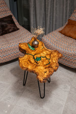 AI-styled view of Zitun Atelier table 075, an olive wood resin small coffee table with turquoise resin veins, viewed from above between two upholstered armchairs.