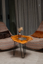 AI-styled view of Zitun Atelier table 076, an olive wood resin side table with white resin center, in a lounge setting with a vase on the tabletop.
