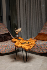 AI-styled view of Zitun Atelier table 078, an olive wood resin small coffee table with black resin veins, in a lounge setting with a vase on the tabletop.