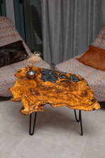 AI-styled view of Zitun Atelier table 080, an olive wood resin side table with black floral resin, viewed from above between two upholstered armchairs.