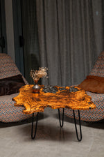 AI-styled view of Zitun Atelier table 080, an olive wood resin side table with black floral resin, in a lounge setting with a vase on the tabletop.