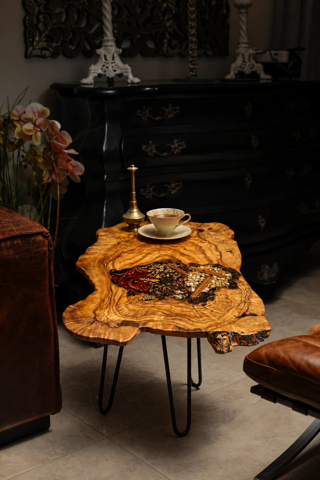 AI-styled view of Zitun Atelier table 082, an olive wood resin side table with red chili spice resin, in a dark interior beside leather seating.