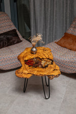 AI-styled view of Zitun Atelier table 082, an olive wood resin side table with red chili spice resin, viewed from above between two upholstered armchairs.