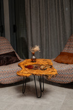 AI-styled view of Zitun Atelier table 082, an olive wood resin side table with red chili spice resin, in a lounge setting with a vase on the tabletop.
