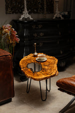 AI-styled view of Zitun Atelier table 084, an olive wood resin side table with white resin center, in a dark interior beside leather seating.