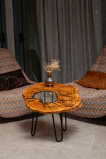AI-styled view of Zitun Atelier table 084, an olive wood resin side table with white resin center, in a lounge setting with a vase on the tabletop.