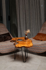 AI-styled view of Zitun Atelier table 085, an olive wood resin side table with white resin live edge, in a lounge setting with a vase on the tabletop.