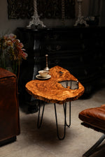 AI-styled view of Zitun Atelier table 086, an olive wood resin side table with white resin live edge, in a dark interior beside leather seating.