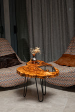 AI-styled view of Zitun Atelier table 086, an olive wood resin side table with white resin live edge, in a lounge setting with a vase on the tabletop.
