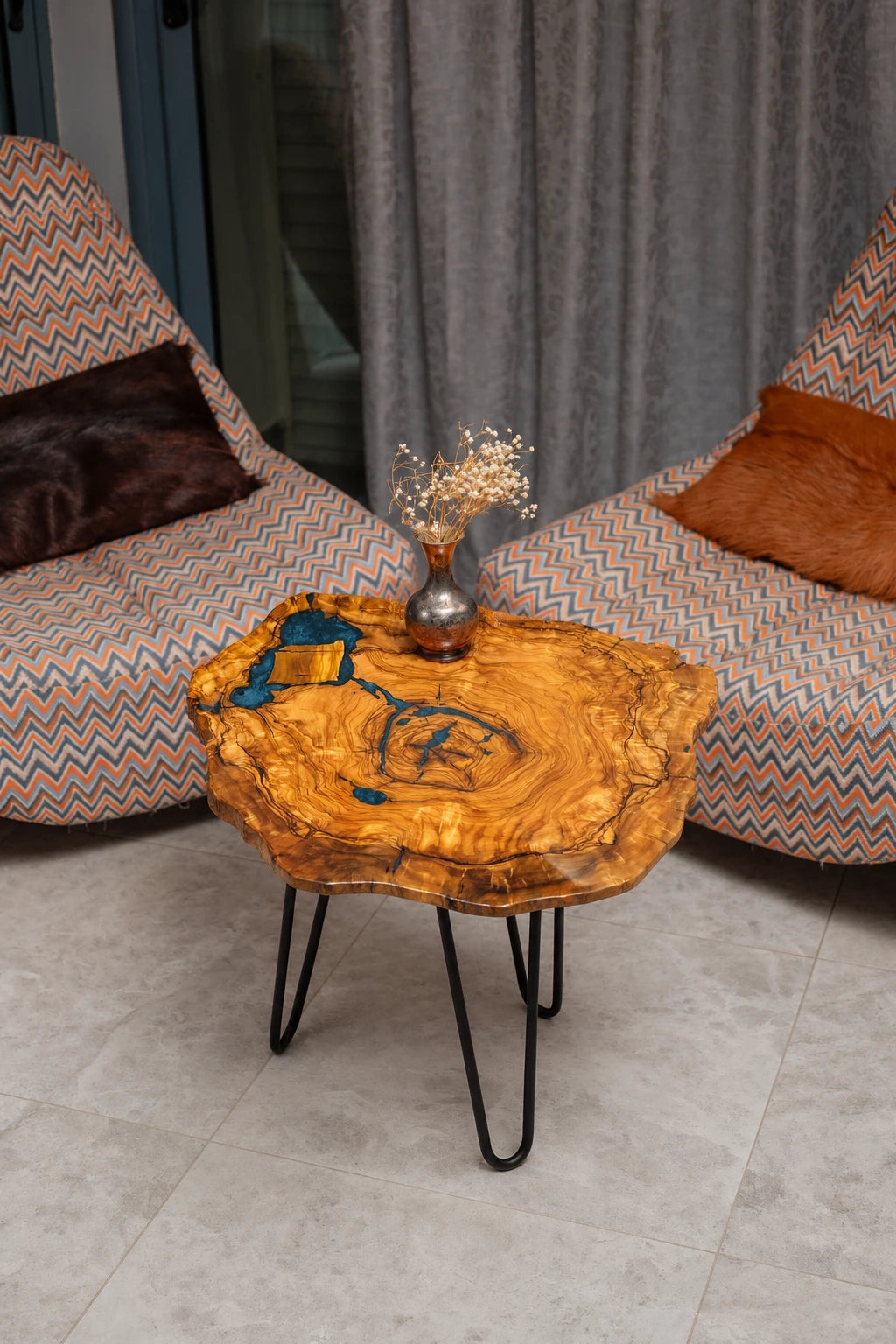 AI-styled view of Zitun Atelier table 087, an olive wood resin side table with blue grey resin veins, viewed from above between two upholstered armchairs.
