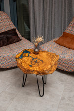 AI-styled view of Zitun Atelier table 087, an olive wood resin side table with blue grey resin veins, viewed from above between two upholstered armchairs.
