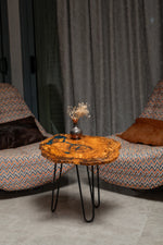 AI-styled view of Zitun Atelier table 087, an olive wood resin side table with blue grey resin veins, in a lounge setting with a vase on the tabletop.