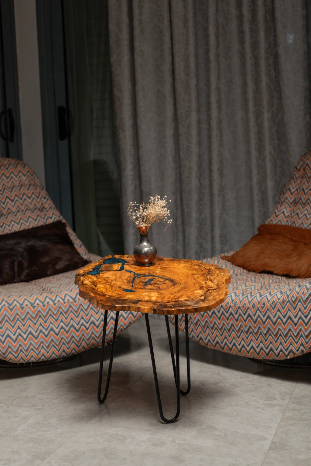 AI-styled view of Zitun Atelier table 087, an olive wood resin side table with blue grey resin veins, in a lounge setting with a vase on the tabletop.