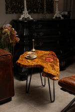 AI-styled view of Zitun Atelier table 088, an olive wood resin side table with copper resin inlay, in a dark interior beside leather seating.