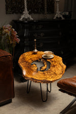 AI-styled view of Zitun Atelier table 089, an olive wood resin side table with white resin center, in a dark interior beside leather seating.