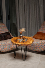 AI-styled view of Zitun Atelier table 089, an olive wood resin side table with white resin center, in a lounge setting with a vase on the tabletop.