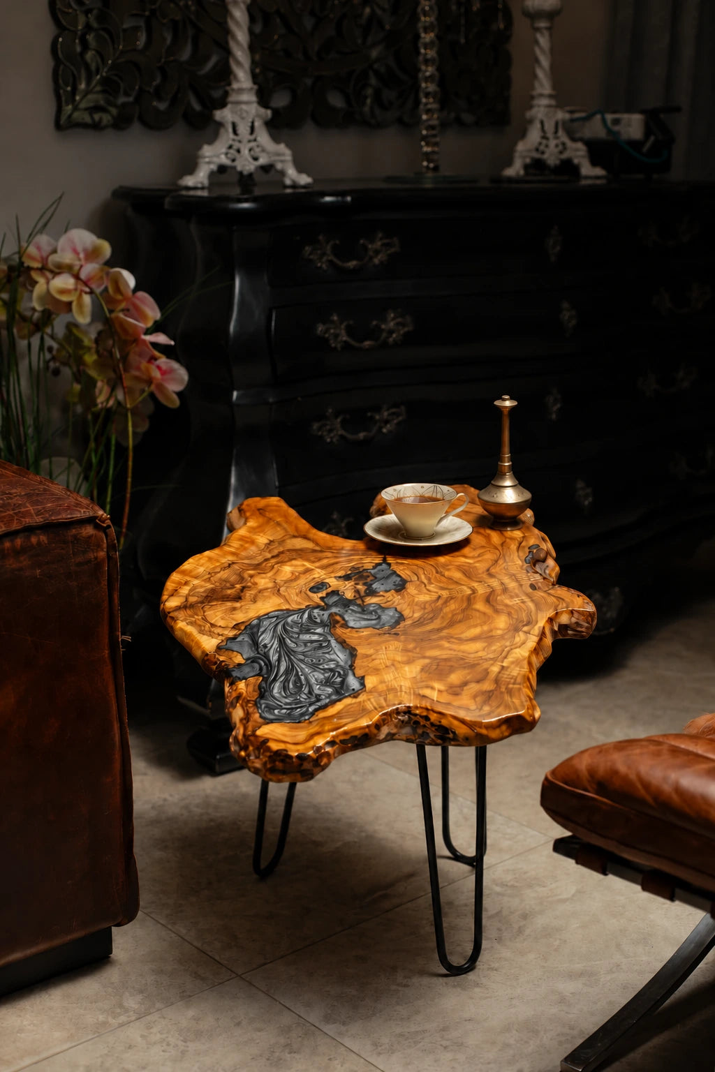 AI-styled view of Zitun Atelier table 091, an olive wood resin side table with black marble resin, in a dark interior beside leather seating.