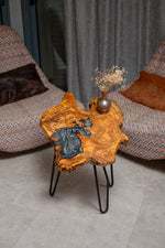 AI-styled view of Zitun Atelier table 091, an olive wood resin side table with black marble resin, viewed from above between two upholstered armchairs.